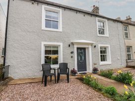 A house with a door and two chairs in front at 1 Brookside in Warcop