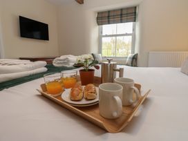 A bedroom with a breakfast tray containing drinks and pastries at 1 Brookside in Warcop