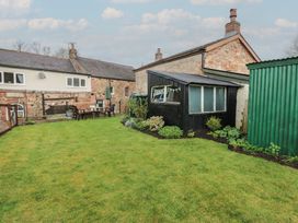 A garden with a table and chairs and a shed at 1 Brookside Warcop