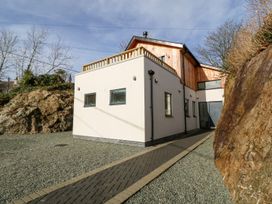 A modern two story house with a pathway and gravel ground between rocks at Ty Chwarel in Menai Bridge