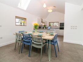 A dining area with a table set with plates and bowls and blue and gray chairs in a kitchen at Ty Chwarel in Menai Bridge