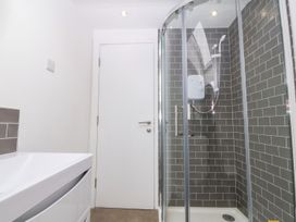 A bathroom with a glass shower enclosure and a white sink at Ty Chwarel in Menai Bridge