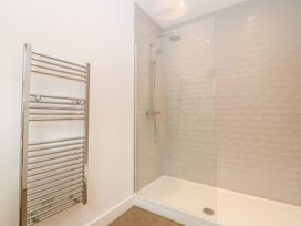 A bathroom with a walk-in shower with glass partition and a wall-mounted towel radiator at Ty Chwarel in Menai Bridge