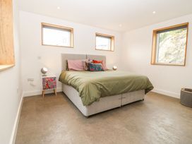 A bedroom with a double bed with green and pink bedding and three windows at Ty Chwarel in Menai Bridge