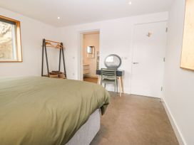 A bedroom with a bed a chair a dressing table an open wardrobe and a bathroom door at Ty Chwarel in Menai Bridge