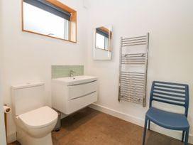A bathroom with a toilet sink mirror towel warmer and a blue chair at Ty Chwarel Menai Bridge