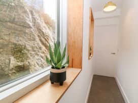 A narrow hallway with a potted plant on a wooden windowsill and a closed white door at Ty Chwarel in Menai Bridge