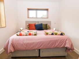 A bedroom with a double bed with colorful pillows and blankets under a window at Ty Chwarel in Menai Bridge