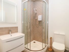 A bathroom with a sink and mirror shower with glass doors and a toilet at Ty Chwarel in Menai Bridge