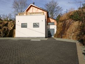 A modern house with a paved driveway and rocky walls on both sides at Ty Chwarel in Menai Bridge