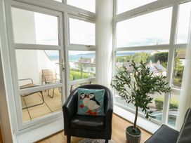 A sunroom with a black chair and green plant at Seaview in Benllech near Red Wharf Bay