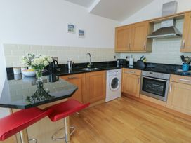 A kitchen with appliances and bar stools at Seaview in Benllech near Red Wharf Bay