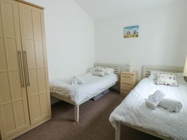 A bedroom with two beds and a wardrobe at Seaview in Benllech near Red Wharf Bay