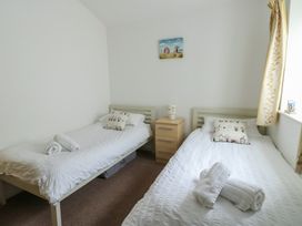 A bedroom with two single beds and a bedside table at Seaview in Benllech near Red Wharf Bay