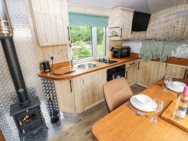 A kitchen with wooden cabinets and a dining table at The Hamper in Felingwm near Carmarthen