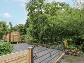 An outdoor area with a wooden cabin and trees at The Hamper in Felingwm near Carmarthen