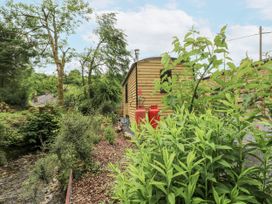 An outdoor view of a wooden cabin with gas canisters and plants at The Hamper in Felingwm near Carmarthen