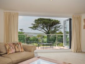 A living room with a sofa and glass door leading to outdoor seating at Bodare 8 Daymer Bay