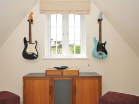 A room with two guitars on walls and a cabinet with a decorative bowl at Bodare 8 Daymer Bay