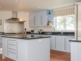 A kitchen with a stove, microwave, and sink at Bodare 8 in Daymer Bay
