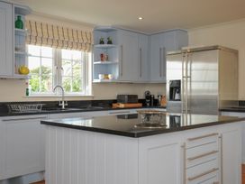 A kitchen with cabinets and refrigerator at Bodare 8 in Daymer Bay