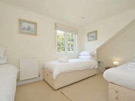 A bedroom with three beds and a window at Bodare 8 in Daymer Bay