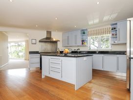 A kitchen with a central island and cabinets at Bodare 8 Daymer Bay