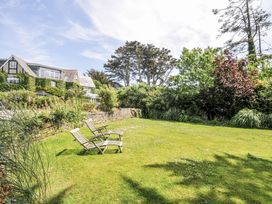 A garden with deck chairs and trees at Bodare 8 in Daymer Bay