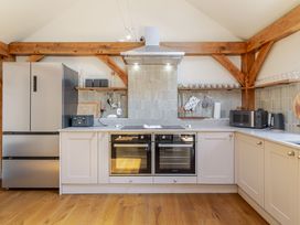 A kitchen with appliances and wooden shelves at Stable Cottage in Burley