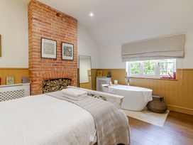 A bedroom with a bed and a bathtub at Stable Cottage in Burley