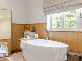 A bathroom with a bathtub and storage box at Stable Cottage in Burley