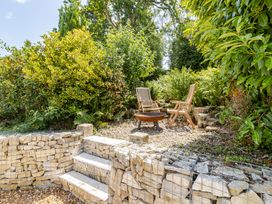 A garden with wooden chairs and a fire pit at Stable Cottage in Burley