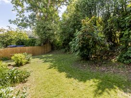 A garden with grass and trees at Stable Cottage in Burley