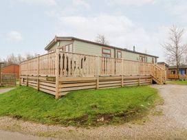 An exterior view of a mobile home with wooden railing and stairs in a grassy area at 6 Sherwood in Carnforth near Tewitfield