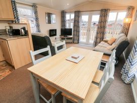 A living room with a wooden dining table and chairs sofa tv and curtains at 6 Sherwood Carnforth near Tewitfield