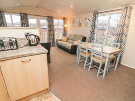 A living room with a sofa dining table and chairs toaster and kettle on kitchen counter at 6 Sherwood Carnforth near Tewitfield
