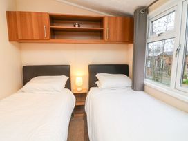 A bedroom with two single beds with white bedding and a small lamp on a nightstand between the beds at 6 Sherwood in Carnforth near Tewitfield
