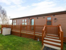 A wooden lodge with a deck and stairs in a grassy area at Finnbars Lodge in Richmond