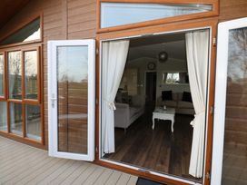 A wooden deck with open glass doors leading to a living room with sofas and a coffee table at Finnbars Lodge in Richmond