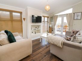 A living room with two sofas a white coffee table and a wall-mounted television at Finnbars Lodge Richmond