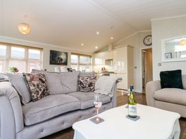 A living room with sofas a white table with a wine bottle and glass and a kitchen in the background at Finnbars Lodge in Richmond