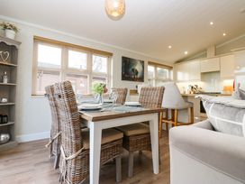 A dining table with wicker chairs set with plates and glasses in an open kitchen and living area at Finnbars Lodge in Richmond