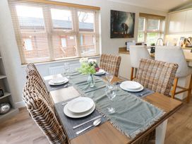 A dining table set with plates glasses and cutlery in a kitchen with rattan chairs and bar stools at Finnbars Lodge Richmond