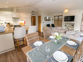 An open plan kitchen and living area with a dining table set with plates and glasses at Finnbars Lodge in Richmond