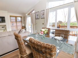 A dining table set with plates glasses and a flower vase next to a sofa and large windows at Finnbars Lodge in Richmond