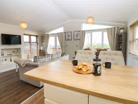 A kitchen island with croissants coffee press and mugs connected to a living room with sofa and TV at Finnbars Lodge in Richmond