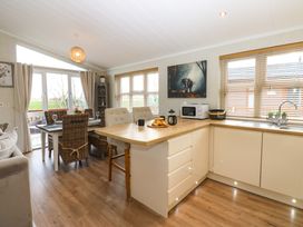 A kitchen and dining area with a wooden floor a dining table with chairs a kitchen counter with a microwave and croissants at Finnbars Lodge in Richmond