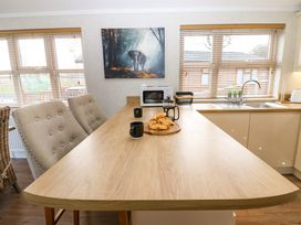 A kitchen with a wooden table with cups and croissants next to windows with blinds at Finnbars Lodge in Richmond