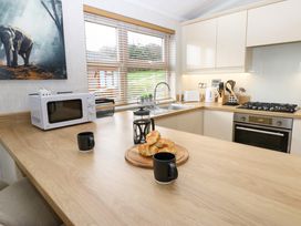A kitchen with wooden countertop croissants on a cutting board black mugs microwave and stove at Finnbars Lodge Richmond