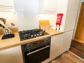 A kitchen countertop with a gas stove oven utensils three jars a cutting board and a fire blanket at Finnbars Lodge in Richmond